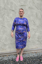 Load image into Gallery viewer, Person wearing a blue floral dress standing against a textured gray wall.
