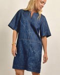 Woman wearing a blue denim dress against a beige background